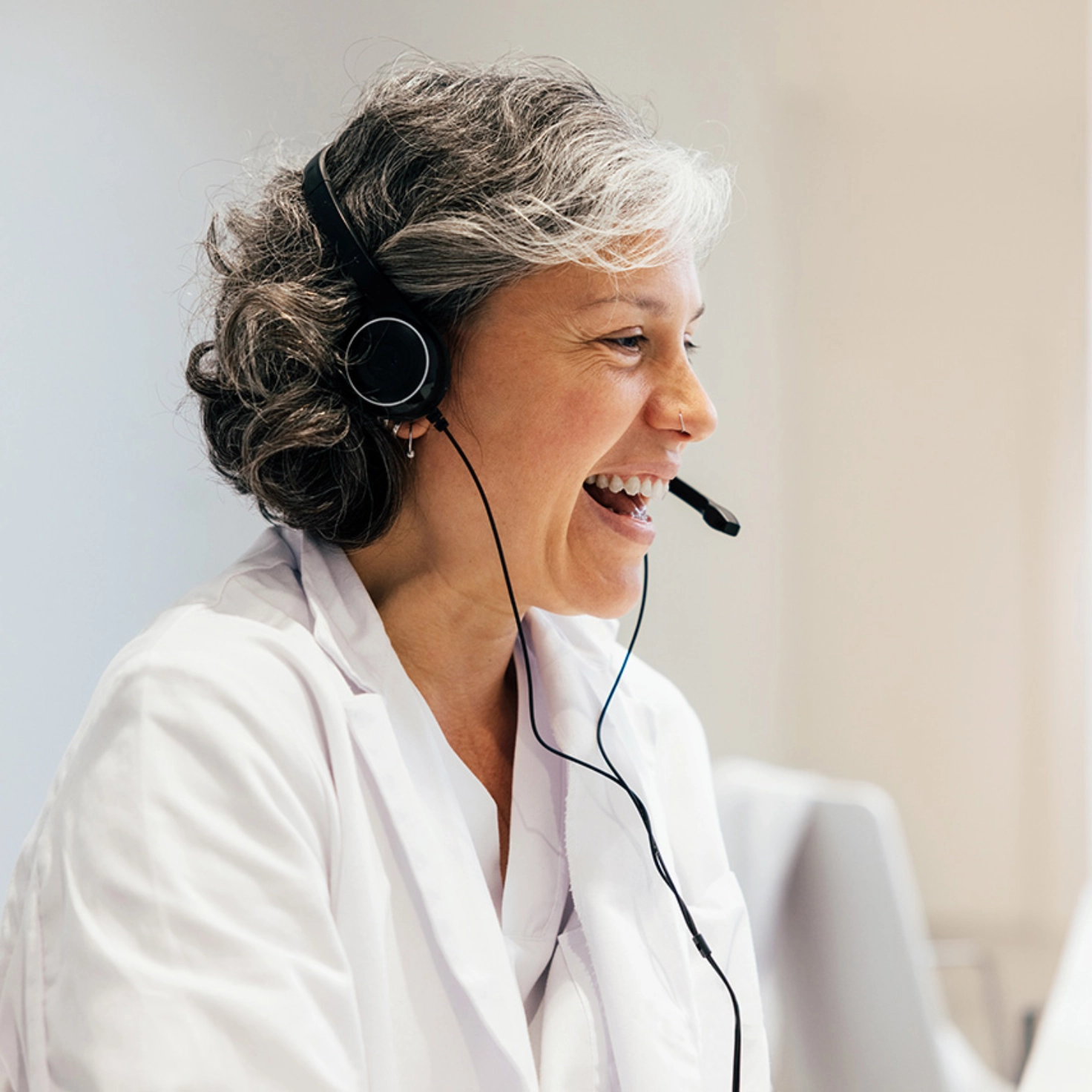 Eine Ärztin telefoniert mit Headset und lacht freundlich