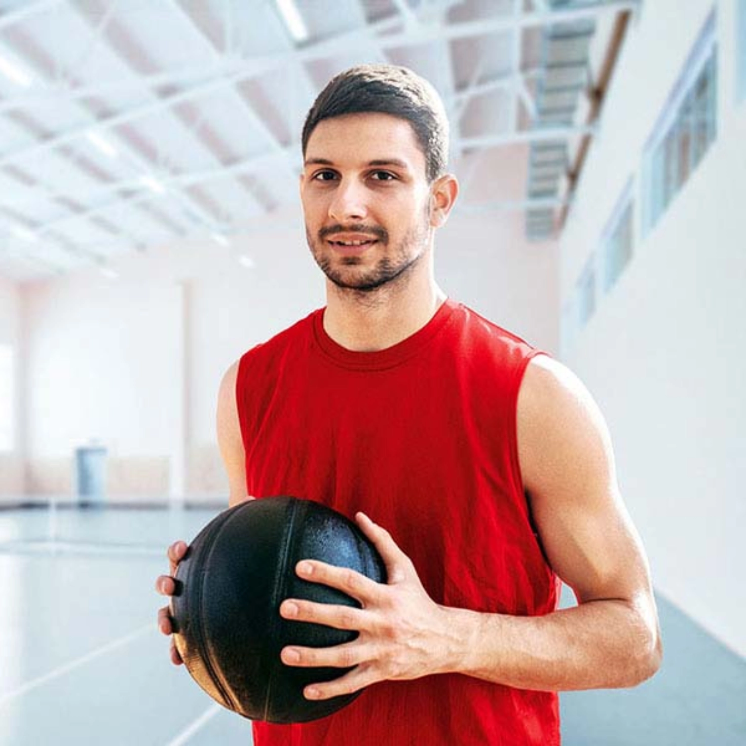 Mann in Turnhalle hält Basketball in den Händen