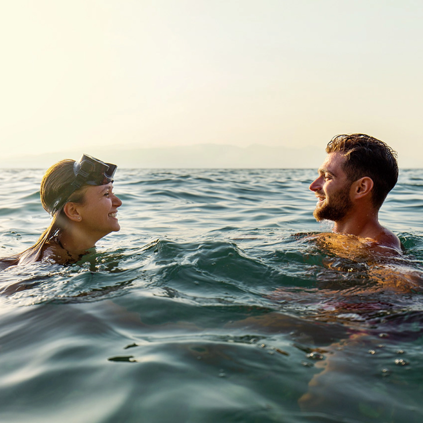 Ein junges Paar badet im See oder im Meer und unterhält sich