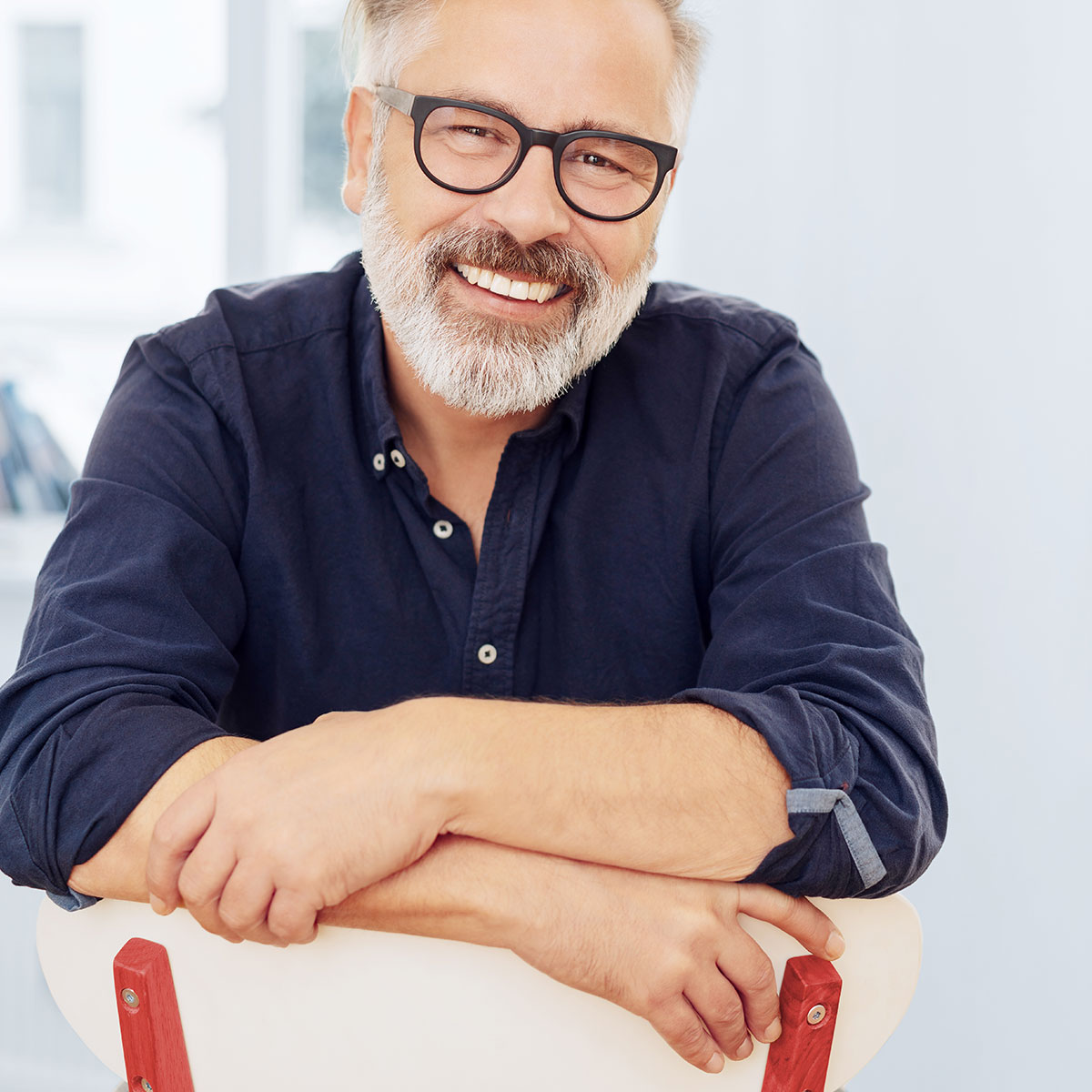 Mann mit Brille auf einem Stuhl sitzend