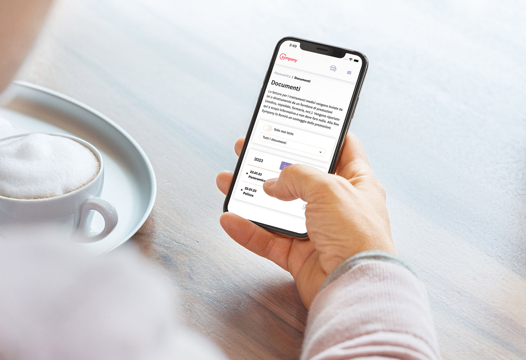 Una persona ha in mano uno smartphone. La schermata mostra il portale clienti mySympany nella versione in lingua italiana.
